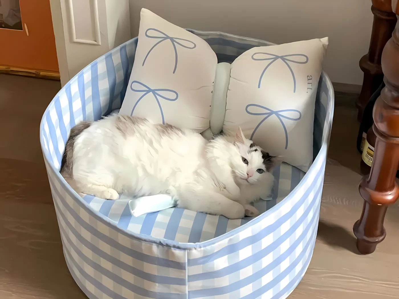 A white cat resting in a striped cat bed